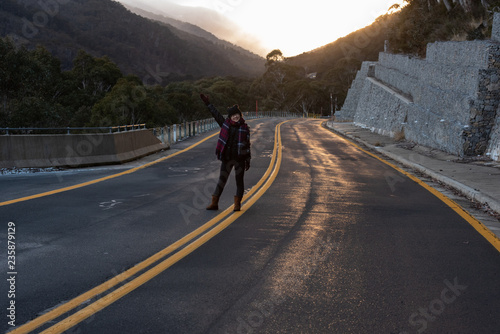 Young woman posing on the road at the crack of dawn with a beautiful sunrise
