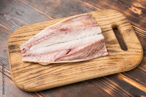Fresh mackerel fish fillet on wooden background. Cooking, cutting fish for cooking.