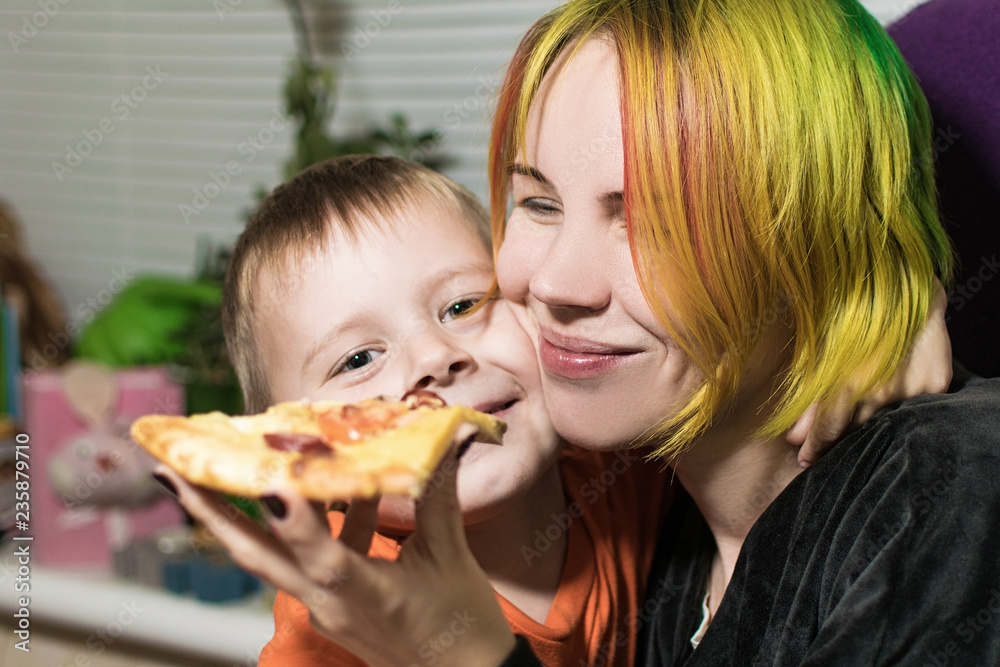 A woman with a child is a little boy son eating pizza together.