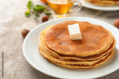Delicious pumpkin pancakes with piece of butter on plate, closeup