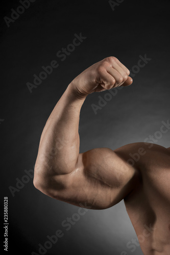 Arm of muscular bodybuilder on dark background