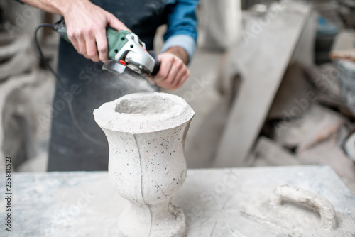 Sculptor in workware grinding stone vase at the working space in the old atmospheric studio. Cropped imaage with no face photo