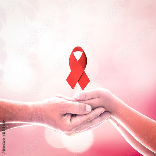World AIDS day concept: Two human hands holding red ribbon. photo