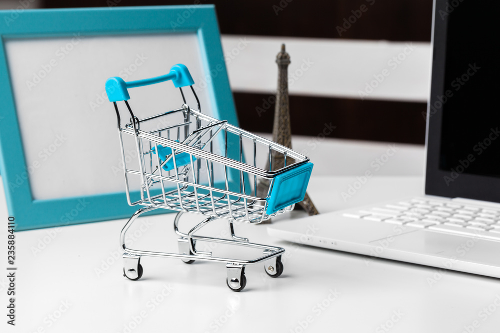 shopping online concept. small toy trolley and gadgets on the table