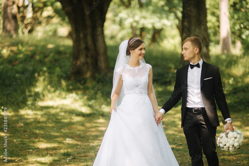 Happy couple walk in the park in their wedding day. Groom and bride Happy couple walk in the park in their wedding day. Groom and bride