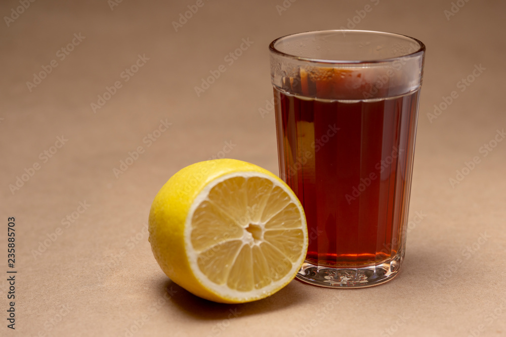Glass with black tea and lemon on a brown background Glass with black tea and lemon on a brown background