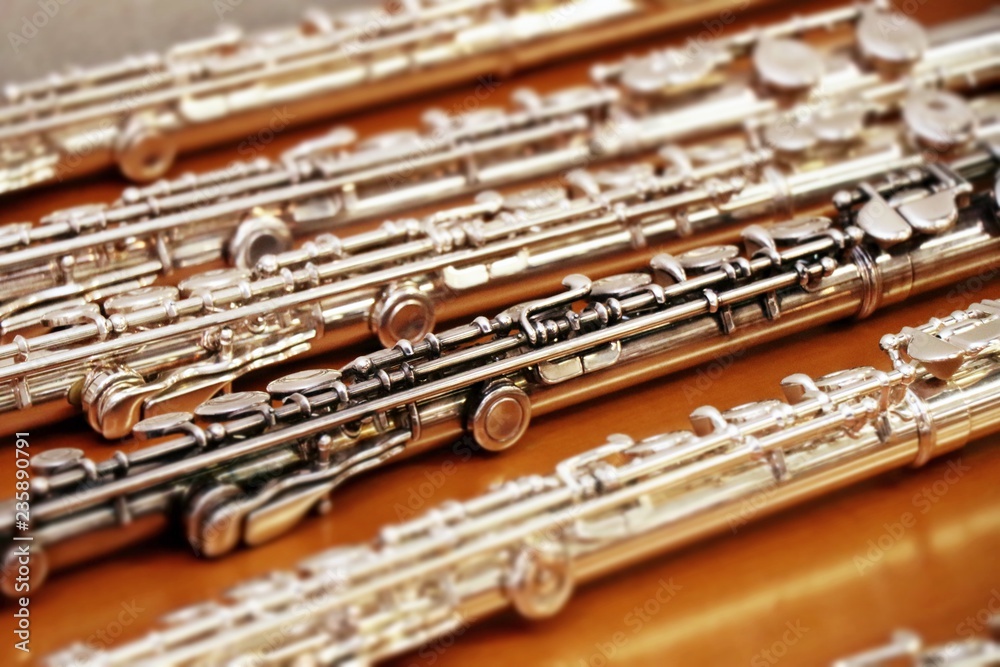 Fototapeta premium Set of silver flutes on the wooden table horizontal close up. Musik background. Selected focus.