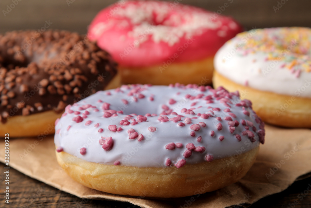 Assorted sweet donuts with icing and dressing close-up on a brown wooden table.
