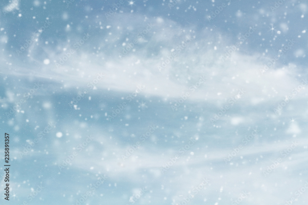 Fototapeta premium Snowy wintry sky. Blurred background of snow falling against cool blue cloudy sky during a winter storm.