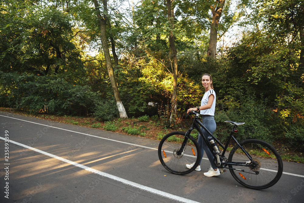 Beautiful young fitness girl walking with bicycle