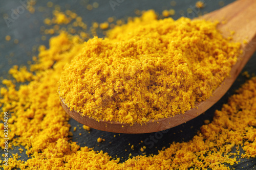 Turmeric powder (Curcuma), also known as Indian saffron, in wooden spoon