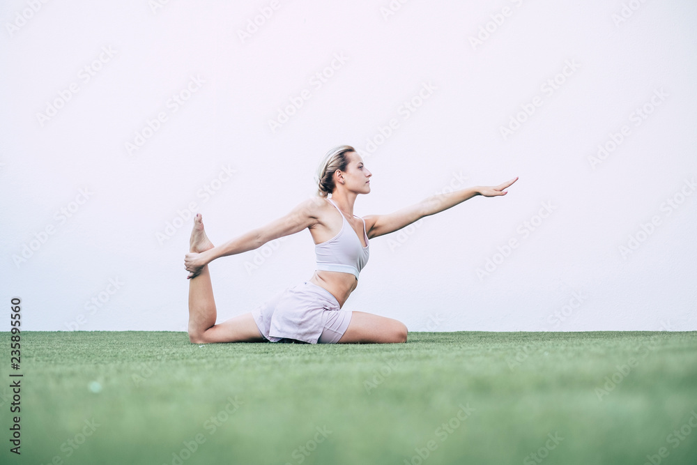 beautiful young blonde girl doing pilates yoga balanced position at home outdoor in the garden on the carpet - minimal pose for perfect body build with fitness and exercises activity beautiful young blonde girl doing pilates yoga balanced position at home outdoor in the garden on the carpet - minimal pose for perfect body build with fitness and exercises activity