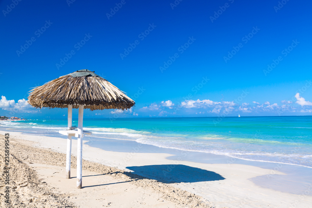 Straw umbrella on empty seaside beach in Varadero, Cuba. Relaxation, vacation idyllic background. Straw umbrella on empty seaside beach in Varadero, Cuba. Relaxation, vacation idyllic background.