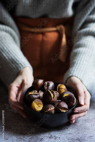 Midsection of woman holding bowl of roasted chestnuts
