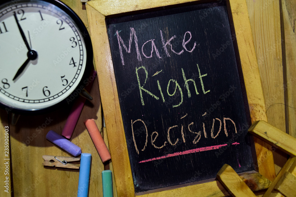 Make Right Decision on phrase colorful handwritten on chalkboard and alarm clock with motivation, inspiration and education concepts. Table background