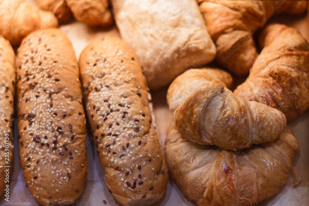 Freshly baked delicious bread and croissants on a wooden shelf, close-up