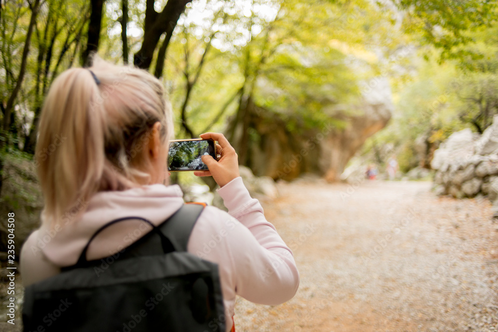 Young Woman taking picture in natural park with smartphone
