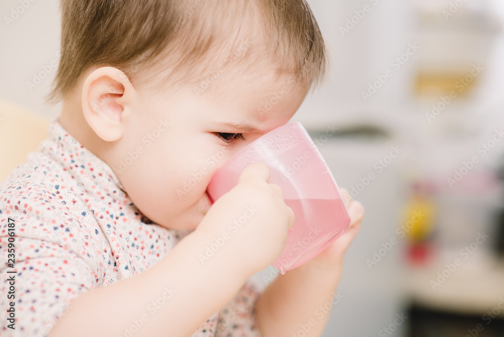 child in the kitchen drinking from a cup of water child in the kitchen drinking from a cup of water