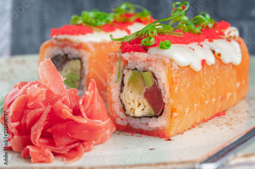 Shizu fusion roll. Wrapped in salmon, with the addition of mozzarella cheese and masago caviar. Stuffing from avocado, Japanese omelet and tuna. photo