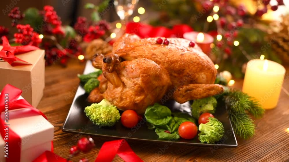 Christmas dinner. Roasted chicken on holiday table, decorated with gifts and burning candles. Roasted turkey over holiday background. Dolly shot, 4K UHD video footage 3840X2160