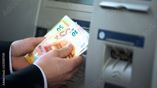 фотографія Man counting euros withdrawn from ATM, 24h service, easy banking operation