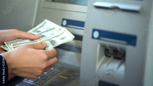 Woman counting dollars withdrawn from ATM, 24h service, easy banking operation