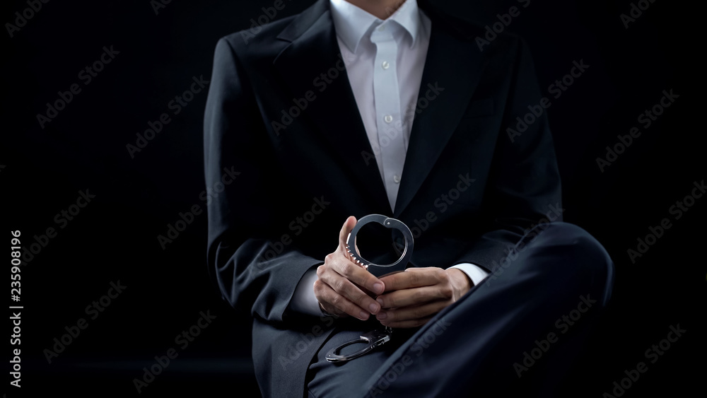 Investigator holding handcuffs in hands, criminal penalty, law and order justice Investigator holding handcuffs in hands, criminal penalty, law and order justice