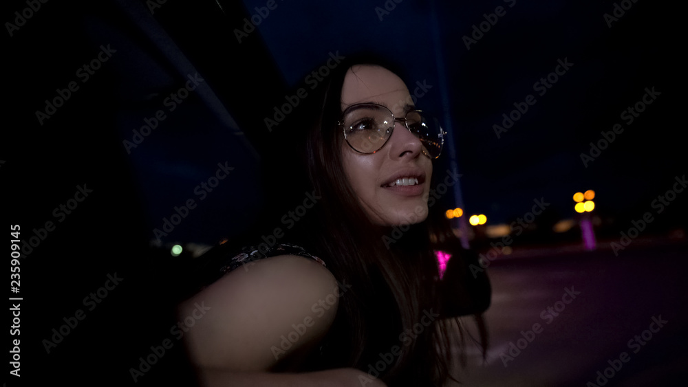 Pretty woman sticking head out of car window, sightseeing of night city, trip Pretty woman sticking head out of car window, sightseeing of night city, trip