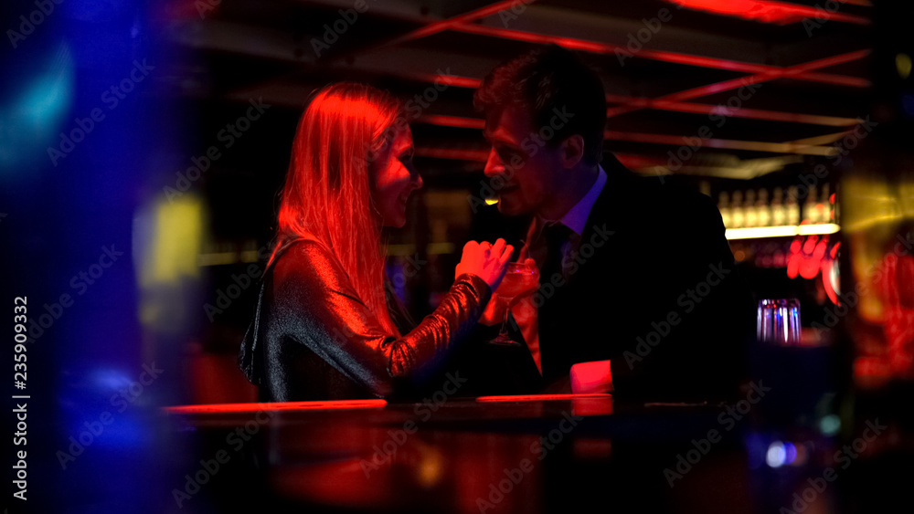 Happy beautiful couple drinking cocktails and flirting in nightclub, romance 