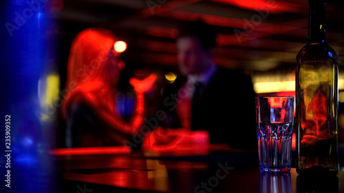 Male and female flirting in nightclub  drinking beverages  blurred background