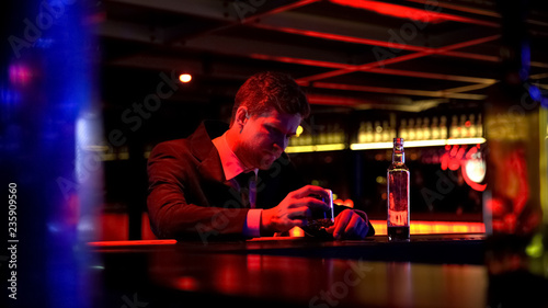 Lonely depressed man drinking whiskey in nightclub, thinking over problems