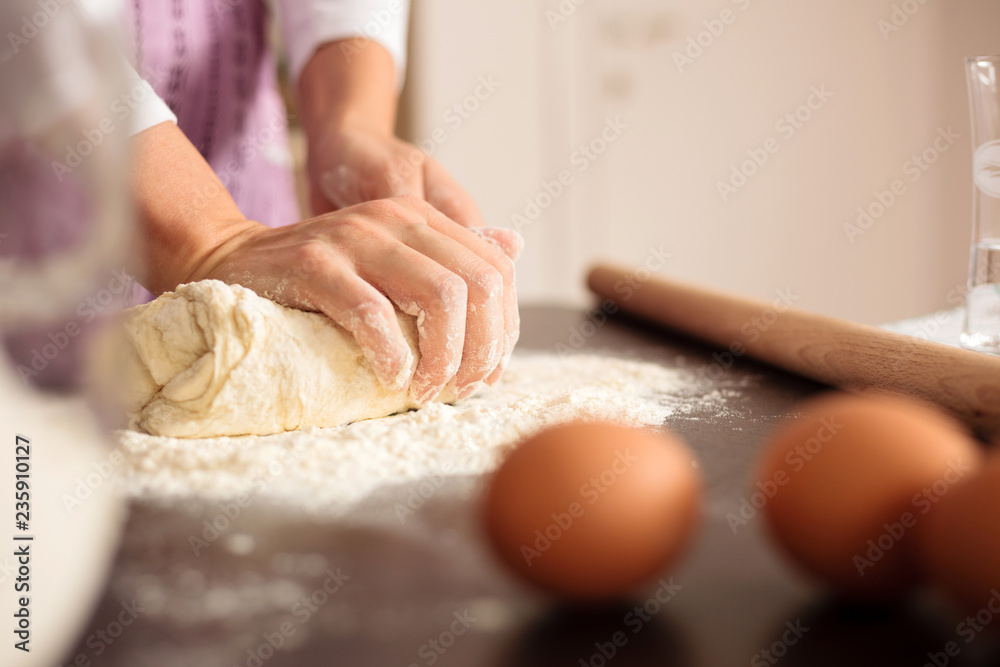 Close up of female hands kneading dough for pasta or pizza in domestic kitchen