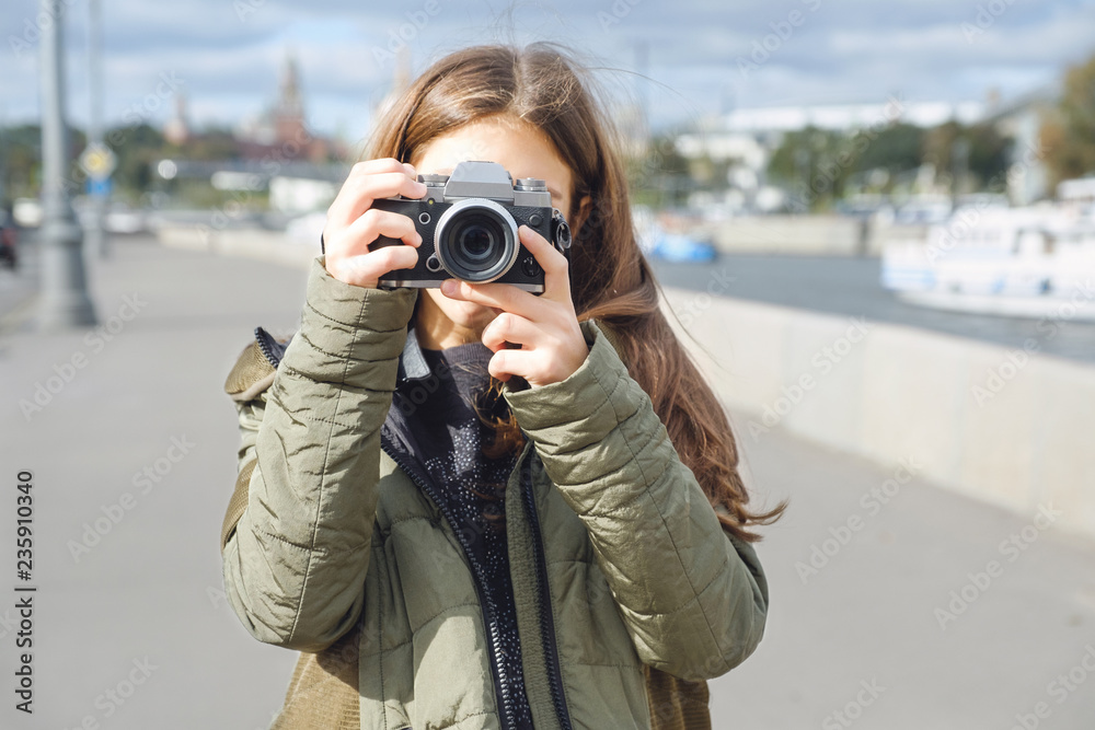 Mirrorless digital camera in the hands of a teenage girl.