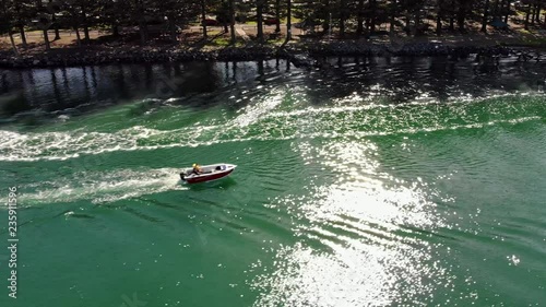 Drone video, profile view catching up to jet ski with fishing boat passing through.  Beautiful scenic footage. photo