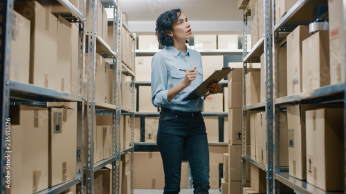 Foto Female Inventory Manager Checks Stock, Writing in the Clipboard