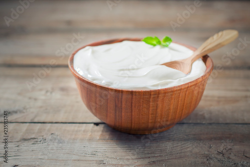 Greek yogurt in a wooden bowl on a rustic wooden table.