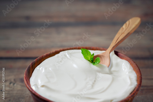 Greek yogurt in a wooden bowl on a rustic wooden table.