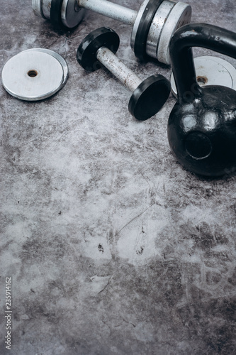 Fitness or bodybuilding concept background. Old iron dumbbells and Kettlebell on grey, conrete floor in the gym. Top view. Healthz lifestyle.