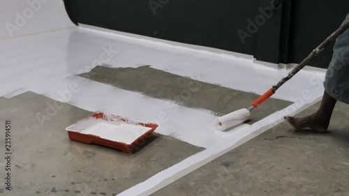First time of worker painting and coating epoxy resin on concrete floor .