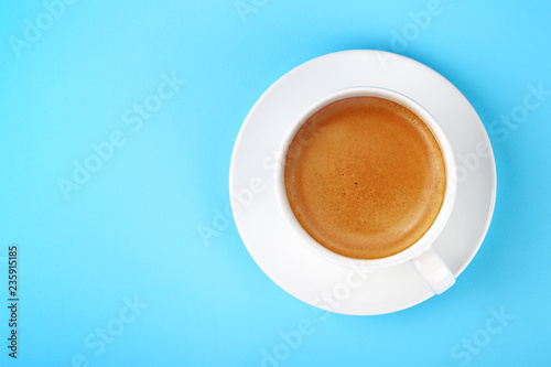 Full white cup of espresso coffee on blue