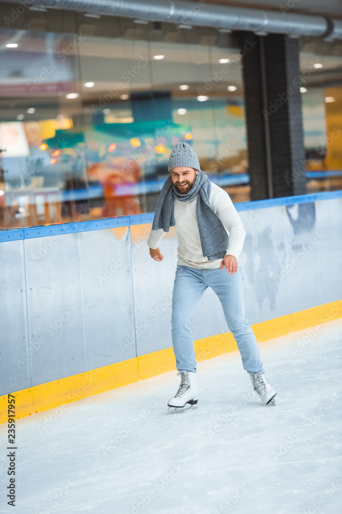 bearded man in knitted hat and sweater skating on ice rink