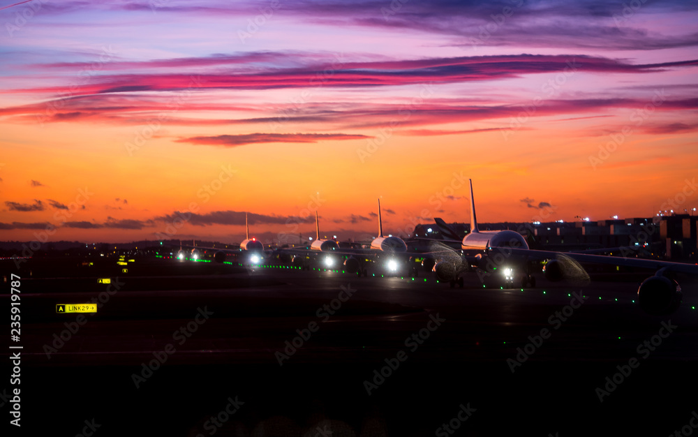 Airplane line up on runway waiting for take off in a beautiful sunset