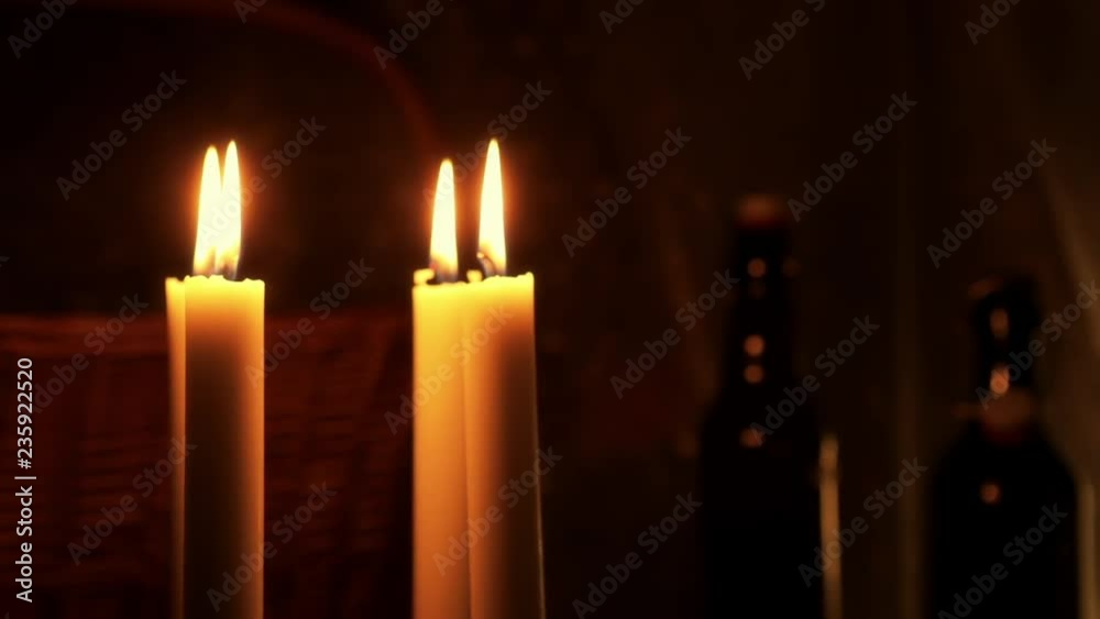 Christmas feeling with candles. Close up on burning candles moving slowly in a circle. In background a basket and some bottles. Soft and star filters used in shooting. Christmas feeling with candles. Close up on burning candles moving slowly in a circle. In background a basket and some bottles. Soft and star filters used in shooting.