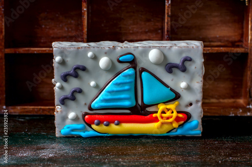Homemade homemade gingerbread cookie in the shape of a boat on the dark dark wooden background.