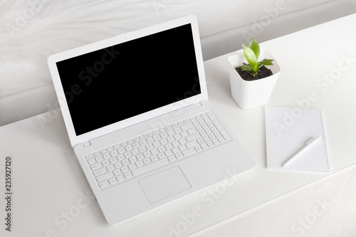 completely white modern workspace with laptop, notepad, plant and pen photo