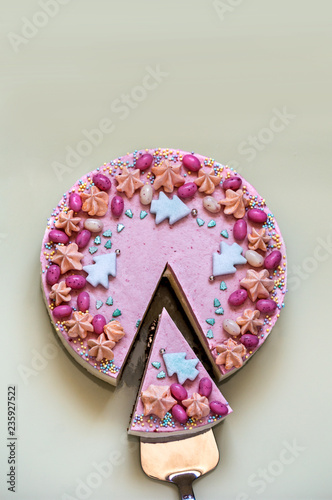 homemade cake decorated with edible Christmas trees and sweets on a bright mirror background