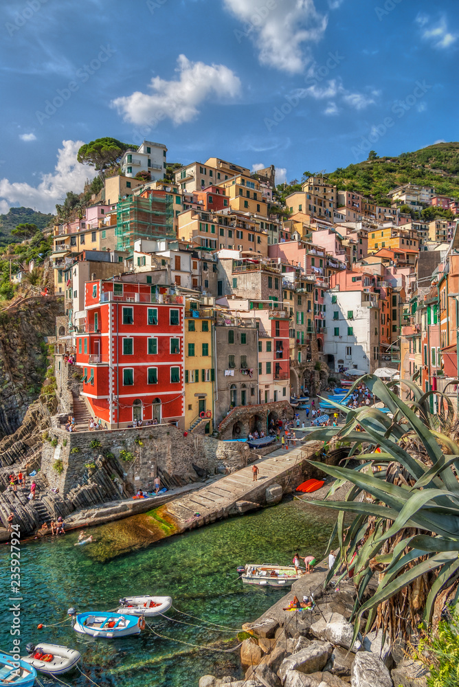 A view of the colorful houses and several boats tied in the small bay of Riomaggiore, one of the five villages in the Italian National Park Cinque Terre. Photo taken August 2018.