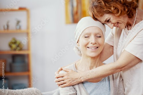 Senior redhead woman hugging her friend who is suffering from leukemia photo