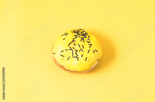 yellow donut isolated on yellow background/Donut in yellow glaze decorated with dark chocolate sticks on yellow background. Top view