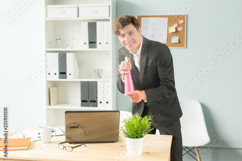 Business people  fun and potted plants concept - young funny businessman watering plant at office